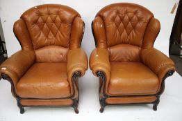 A pair of contemporary tan leather wingback armchairs.