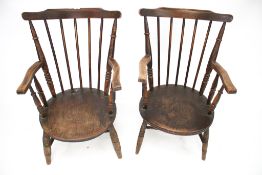 A pair of rustic stained pine elbow chairs.