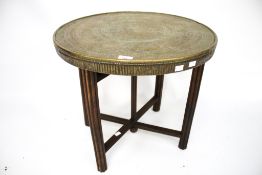 A middle eastern Islamic brass top folding side table. Wooden base with round fluted supports.