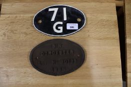 An oval cast iron train works plate and a plaster shed plate.
