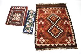 Two rugs and a needlepoint wall hanging.