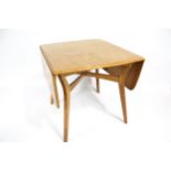 A mid-century light oak drop leaf dining table.