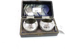 A pair of white metal napkin rings. Embossed with scenes of birds, in a fitted box, 52.