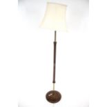 A mid-century modern standard lamp. Having a circular mahogany base with part metal and wood column.