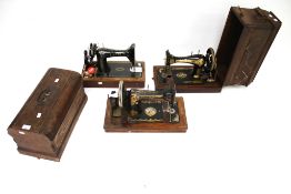 Three vintage hand crank sewing machines.