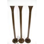 A set of three brown metal tubular uplighter floor lamps.
