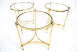 Hollywood Regency : A set of three circular brass and glass topped tables.
