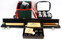Two sets of carpet bowls, a set of Jacques garden bowls and a two piece snooker cue.
