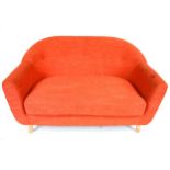 A contemporary orange two seater sofa. Raised on turned supports.