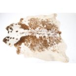 A brown and white cow hide rug.