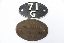 An oval cast iron train worksplate and a plaster shedplate.