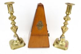 A metronome and a pair of brass candlesticks. The metronome in a mahogany case, H22.