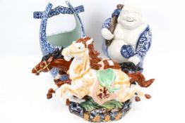 A laughing buddha, a ceramic well bucket and a ceramic horses group figure.