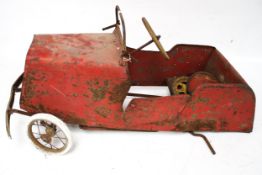 A child's vintage red metal ride on pedal car.