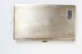 A silver rectangular engine-turned cigarette case.