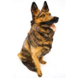 A life size model of a German Shepherd dog made of painted and varnished plaster-style material.
