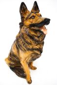A life size model of a German Shepherd dog made of painted and varnished plaster-style material.