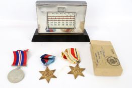A silver mounted perpetual calendar and three WWII medals.