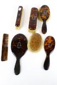 A tortoiseshell vanity dressing table set. Including brushes and a hand mirror, etc.