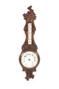 A late Victorian carved oak two glass wall aneroid barometer. With porcelain dial backs.