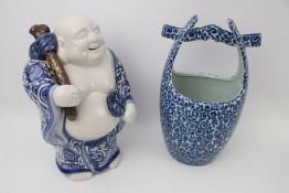 A blue and white glazed ceramic laughing buddha and a ceramic well bucket.