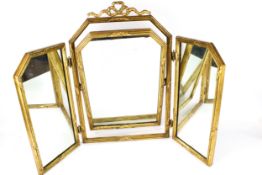 A gilt framed triple folding dressing table mirror. The frame surmounted by a ribbon, H63.