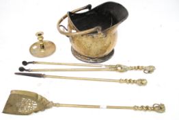 A set of three brass fire irons, a coal scuttle and a candlestick.