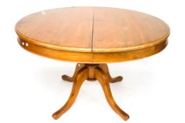 An extending circular dining table. On a single central pedestal with four legs.