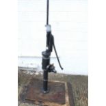 A very large cast iron well water pump. Painted black, mounted on board.
