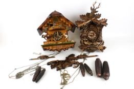 Two cuckoo clocks. Both made in Germany, with Alpine theme cases, with pine come weights, pendulums.