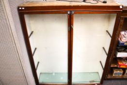 A vintage shop display cabinet. Wooden with two glazed doors, three glass shelves.