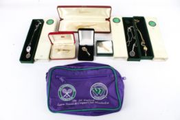 A collection of Wimbledon tennis items. Including bags, necklaces, pendants and brooches.