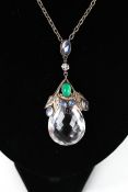 An Arts and Crafts rock crystal and gem set pendant. The large faceted rock crystal drop (approx.