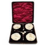 A set of four Edwardian silver small round salts and spoons.