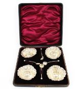 A set of four Edwardian silver small round salts and spoons.