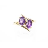 A vintage 9ct gold and oval amethyst two-stone cross-over ring. Hallmarks for Birmingham 1971, 2.