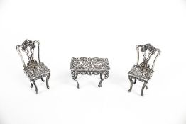 A pair of Edwardian silver miniature chairs and a dressing table.