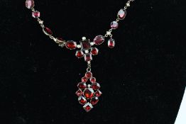 A late 19th century gold, half-pearl and flat-cut garnet collet necklace in 18th century style.