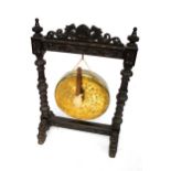 A Victorian oak and large brass riveted dinner gong on a heavily carved stand.