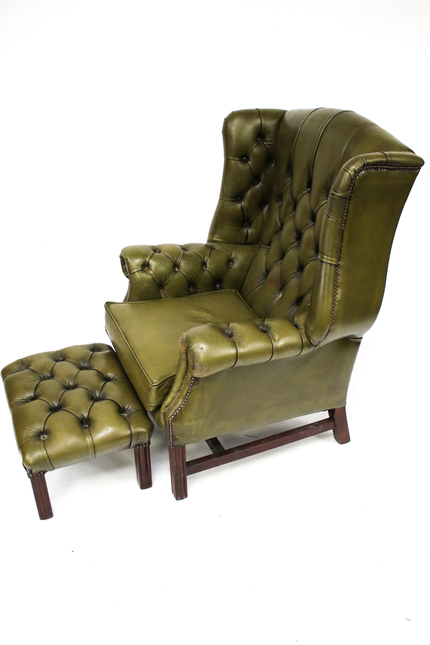 A 20th century Georgian Style green leather button back upholstered wing back armchair and