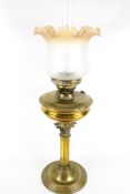 A brass oil lamp with shade and chimney.