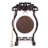 A 19th century central Chinese dinner gong. Forged, carved oak frame and a leather ended beater.