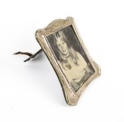 An Edwardian silver mounted shaped-rectangular easel-back photograph frame.