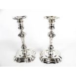 Two very similar George II cast silver shaped-square candlesticks.