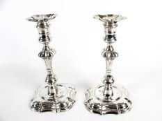 Two very similar George II cast silver shaped-square candlesticks.
