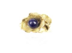 A flower ring set with a blue bead in unmarked yellow metal. The mount damaged, 4.