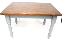A vintage dining table. The stained wooden top mounted on grey painted turned legs.