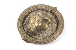 A vintage brass door knocker modelled as a lion's face within a wreath.