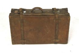 A vintage brown leather suitcase with straps.