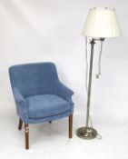 A light blue upholstered contemporary armchair with a standard lamp.